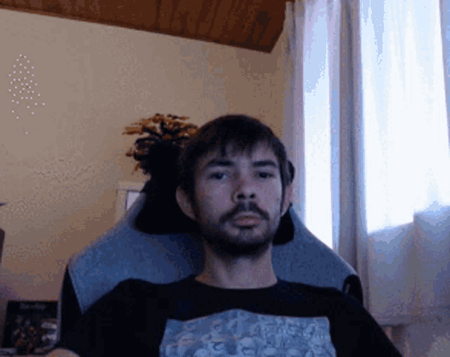 a man with a beard is sitting in a chair wearing a t-shirt that says ' i love you '