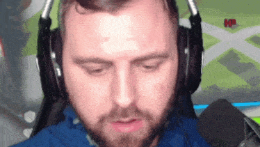 a man with a beard wearing headphones and a microphone in front of a screen that says kp