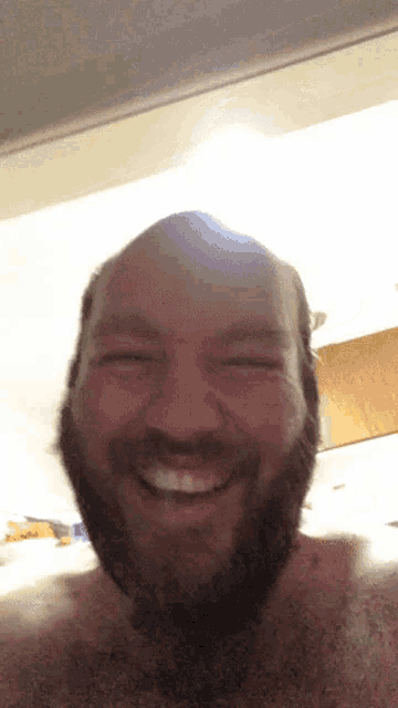 a shirtless man with a beard is smiling