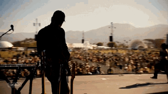 a man stands on a stage in front of a crowd at a music festival with the words coachella on the bottom right