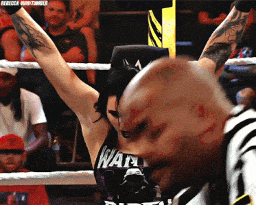 a female wrestler wearing a shirt that says ' way ' on it stands in a boxing ring