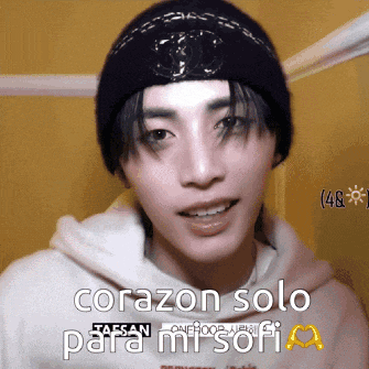 a young man wearing a black beanie and a white hoodie says corazon solo para mi sofi
