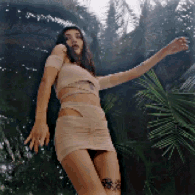 a woman with a tattoo on her leg is standing in front of a palm tree