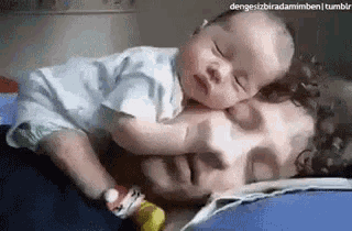 a man is laying on a bed with a baby on his chest .