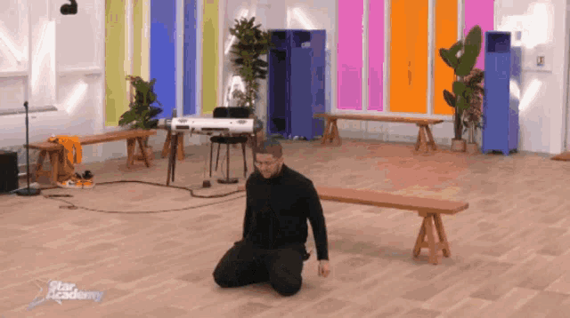 a man is kneeling down in a room with the word star academy written on the bottom