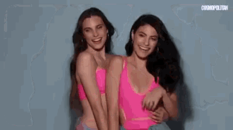 two women in pink bikinis are standing next to each other .