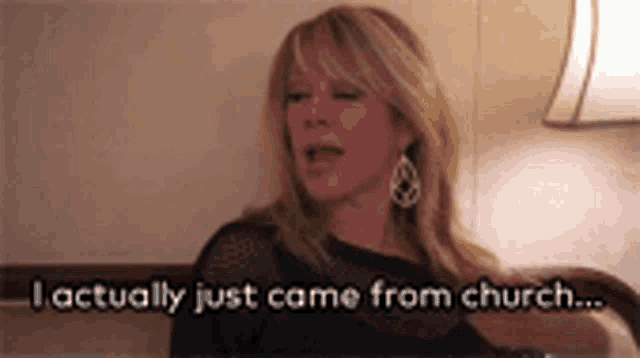 a woman is sitting on a bed and talking about church .