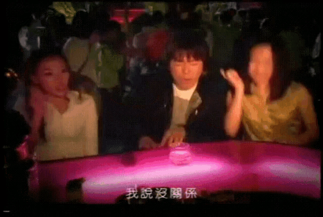 a group of people standing around a pink table with chinese characters on it
