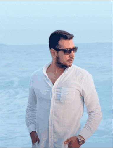 a man wearing sunglasses and a white shirt stands on a narrow street
