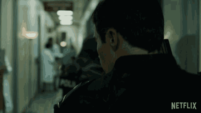 a man in a police uniform is walking down a hallway with a netflix logo in the corner