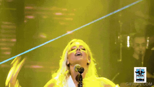 a woman singing into a microphone in front of a panic sign