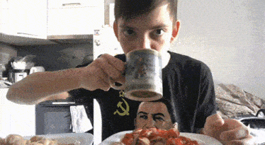 a young boy drinking from a mug with a picture of a man on it