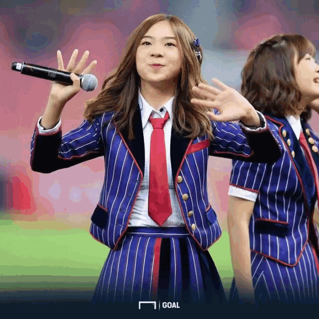 a girl in a blue and red striped suit holds a microphone in her hand