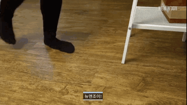 a person 's feet are shown on a wooden floor with a new n joy logo in the background