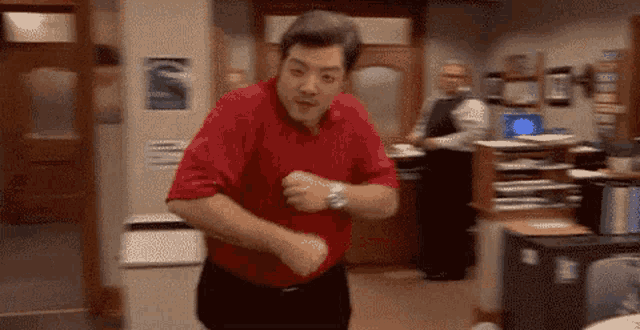a man in a red shirt is dancing in a room with other people .