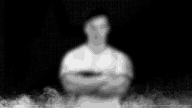 a blurry picture of a man with his arms crossed