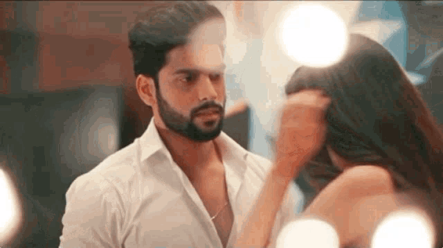 a man and a woman are looking at each other in front of a mirror in a room .