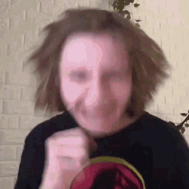 a man with long hair is making a funny face while wearing a black shirt with a dinosaur on it .