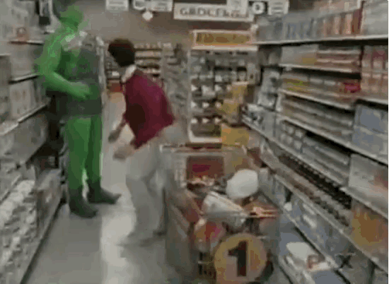 a man in a green costume is pushing a cart in a grocery store .