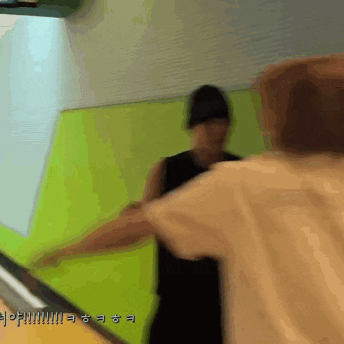 a blurry picture of two people standing next to each other with a green wall in the background