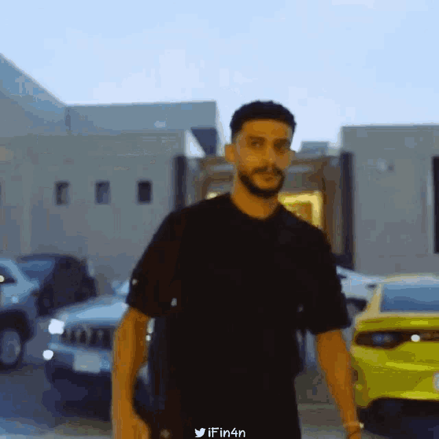 a man with a beard and glasses is standing in front of a building .