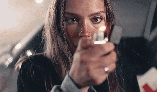 a woman is lighting a cigarette with a lighter in her hand .