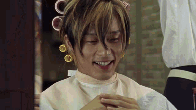 a man with curlers in his hair is smiling and wearing earrings