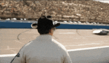 a man in a cowboy hat watches a race on a track