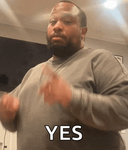 a man in a grey sweater says yes with his hands