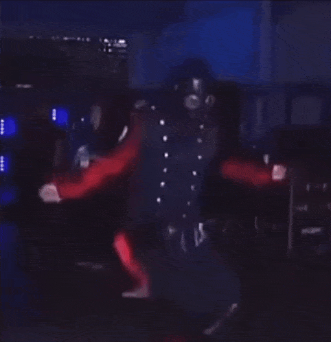 a man in a black and red outfit is dancing on a stage