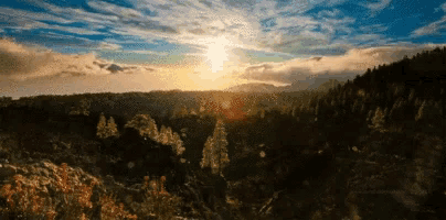 the sun is shining through the clouds over a mountain range