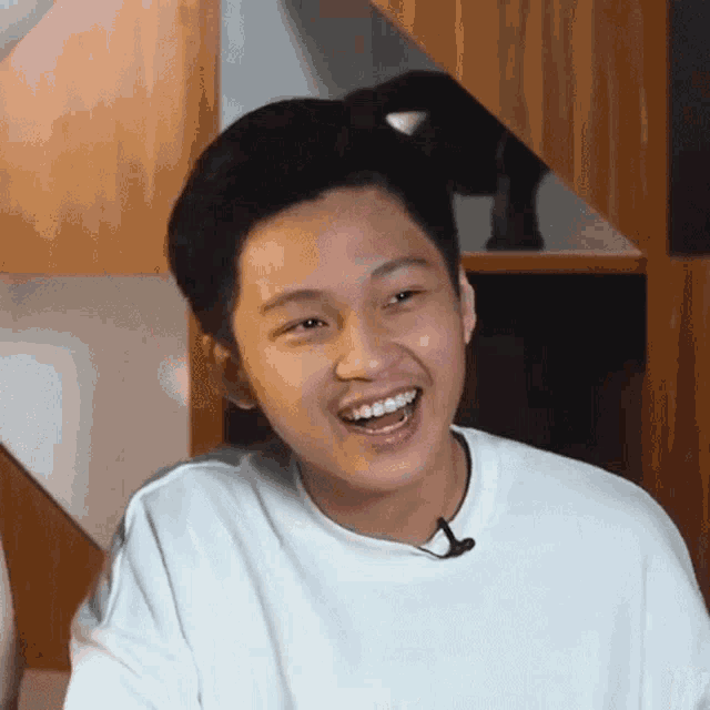a young man with braces on his teeth is smiling and wearing a white shirt .