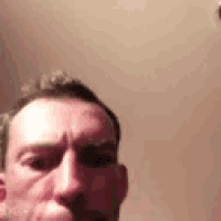 a man is taking a selfie in front of a mirror with his mouth open .