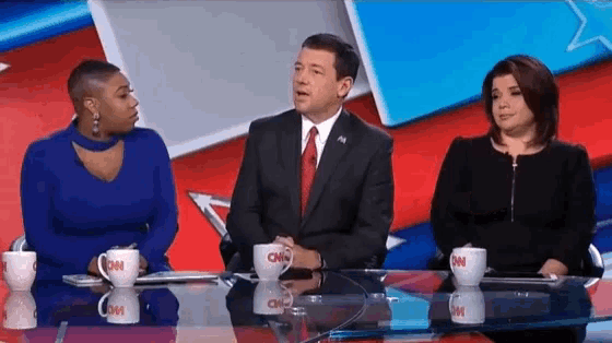 three people sitting at a table with cnn mugs