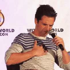 a man is holding a microphone and giving a thumbs up sign