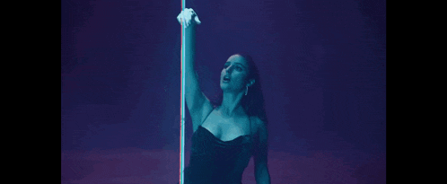 a woman in a black dress is holding a light bulb in a dark room .
