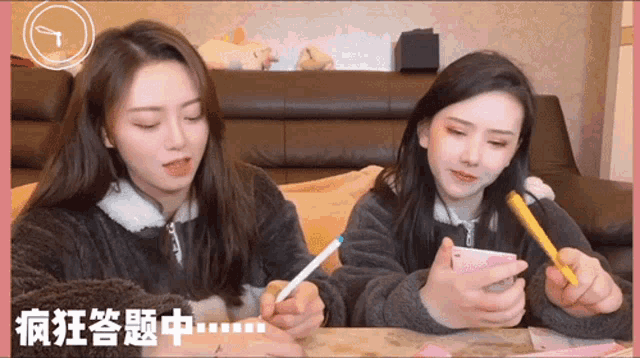 two women are sitting at a table with chinese writing on the bottom