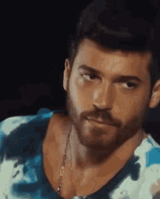 a close up of a man with a beard wearing a blue and white tie dye shirt .