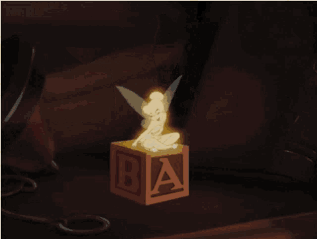 a fairy is sitting on a block with the letter a on it