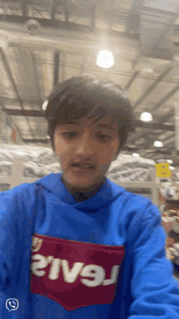 a young boy wearing a blue levi 's hoodie takes a selfie