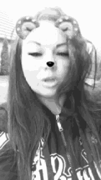a black and white photo of a woman wearing a hoodie and a bear face mask .