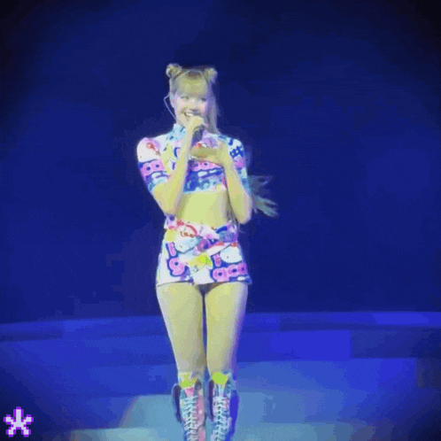 a woman in a hello kitty outfit is singing into a microphone on stage