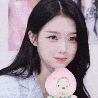 a woman is holding a stuffed animal that has a peach hat on it