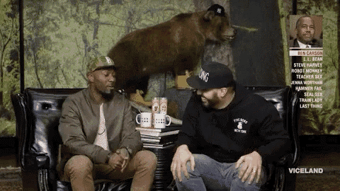 two men are sitting on a couch in front of a stuffed bear that says " viceland " on it