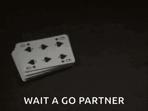 a stack of playing cards on a table with the words `` wait a go partner '' written above them .