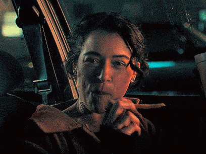 a woman is sitting in a car holding a piece of meat in her hand