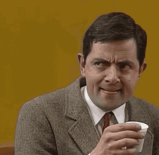 a man in a suit and tie is drinking a cup of coffee .