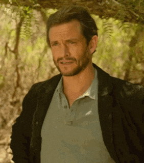 a man with a beard wearing a black jacket and a blue polo shirt