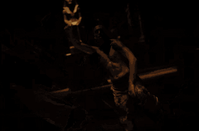 a shirtless man with a necklace around his neck is dancing in a dark room