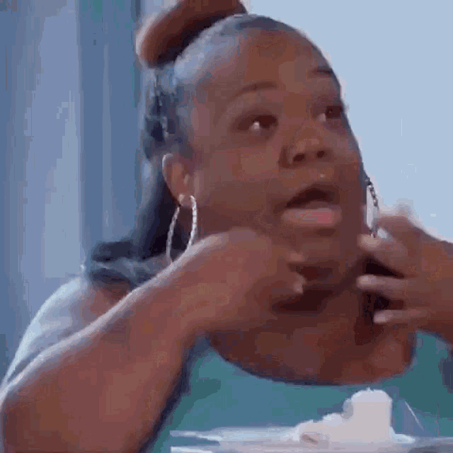a woman is eating a piece of cake and making a funny face while sitting at a table .